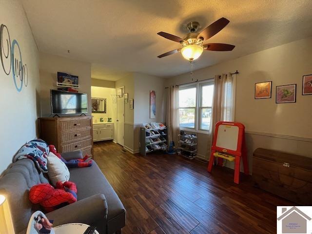 bedroom with a ceiling fan, connected bathroom, a textured ceiling, and wood finished floors