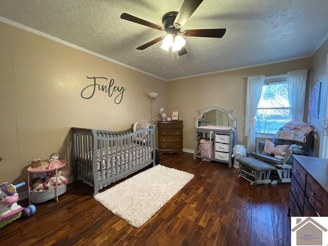 bedroom featuring a nursery area, crown molding, a textured ceiling, and hardwood / wood-style floors