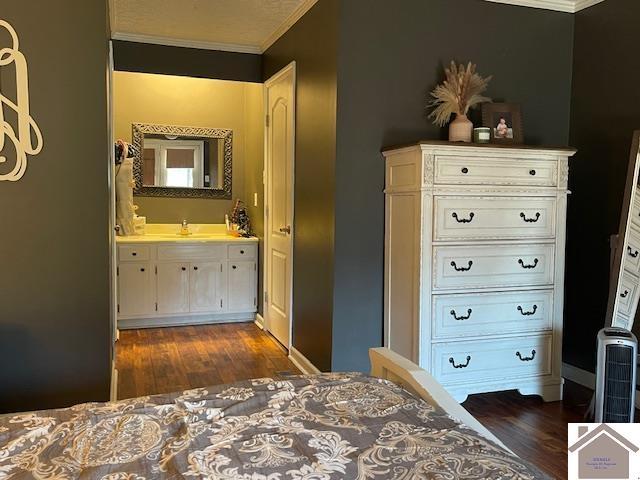 unfurnished bedroom with ornamental molding, ensuite bathroom, and dark wood-style floors