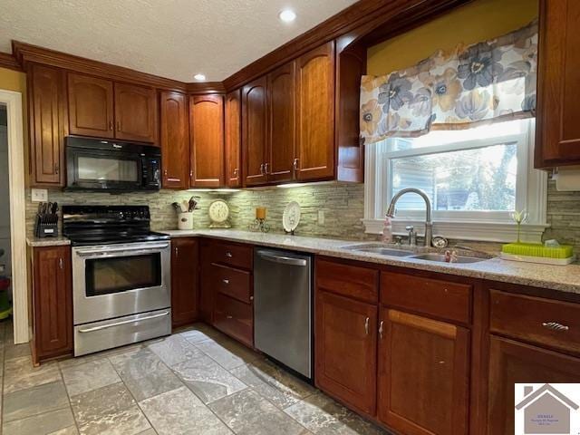 kitchen featuring tasteful backsplash, appliances with stainless steel finishes, stone finish floor, a sink, and light stone countertops