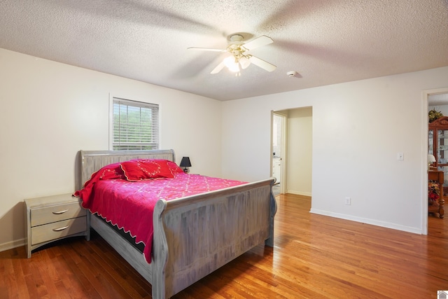 bedroom featuring a textured ceiling, ceiling fan, wood finished floors, and baseboards