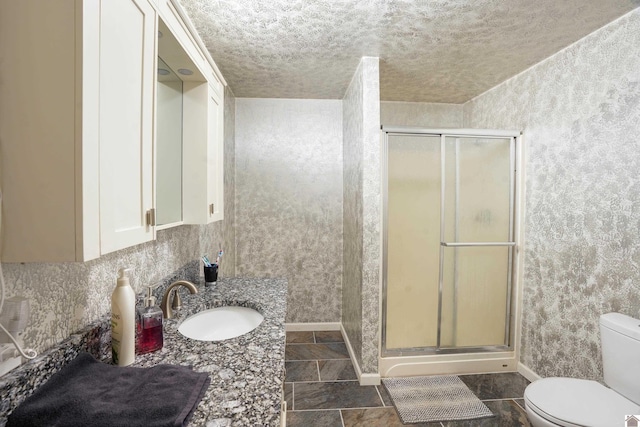 bathroom featuring toilet, a stall shower, a textured ceiling, vanity, and baseboards