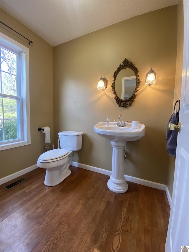 bathroom with toilet, baseboards, visible vents, and wood finished floors