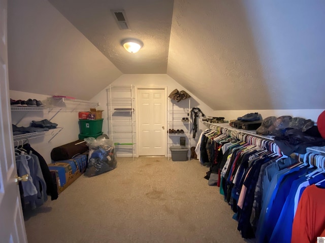 spacious closet with lofted ceiling, carpet flooring, and visible vents