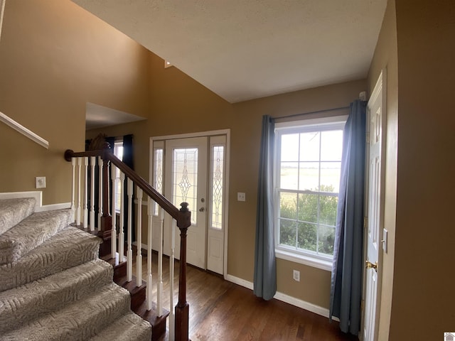 foyer entrance with baseboards, stairway, vaulted ceiling, and dark wood-type flooring