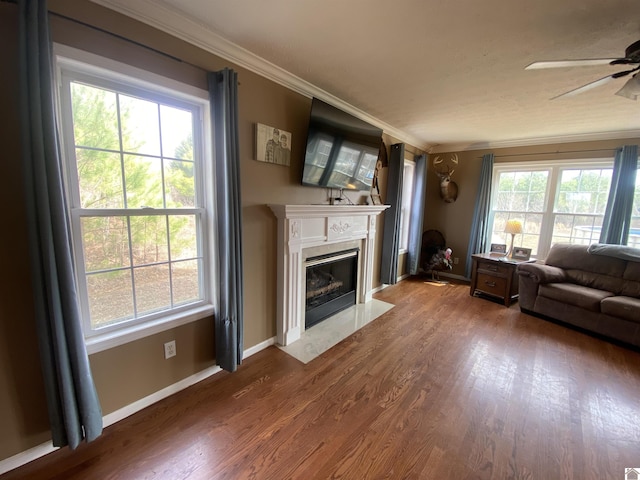 unfurnished living room with baseboards, a ceiling fan, ornamental molding, dark wood-style flooring, and a fireplace