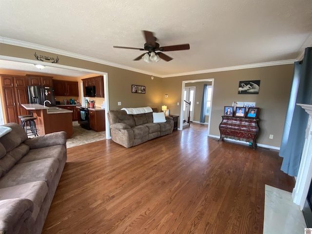 living room with dark wood-style floors, baseboards, ornamental molding, and a ceiling fan