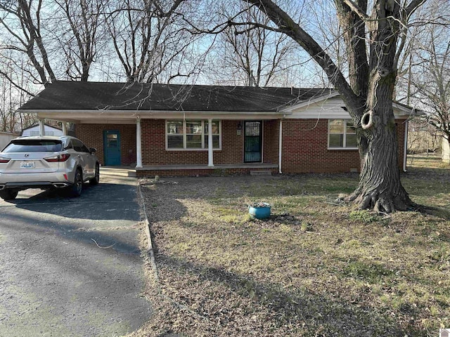 single story home featuring driveway, covered porch, a carport, and brick siding