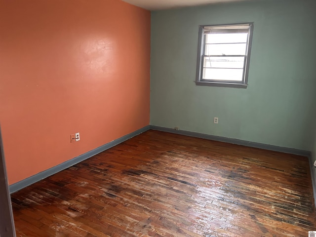 spare room with dark wood-type flooring and baseboards