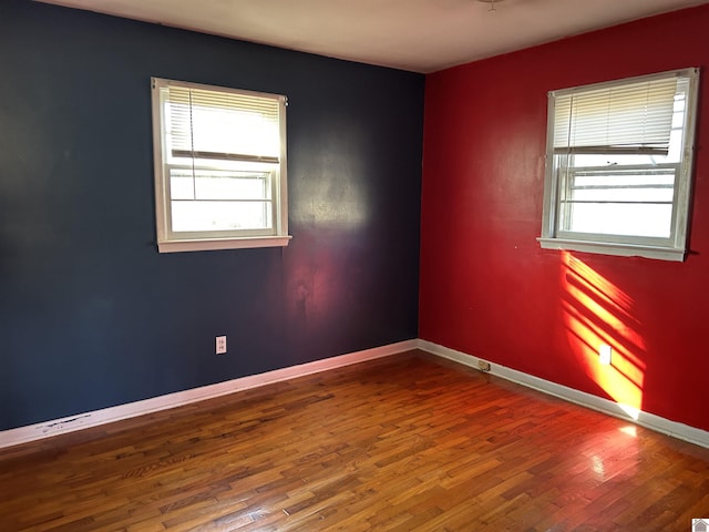 empty room featuring a healthy amount of sunlight, baseboards, and wood finished floors