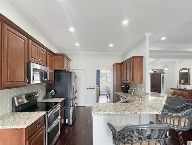 kitchen featuring light stone counters, appliances with stainless steel finishes, a kitchen breakfast bar, and a sink