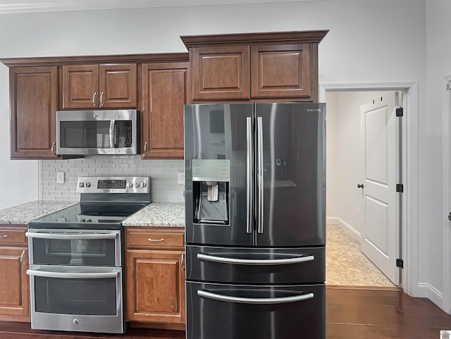 kitchen with stainless steel appliances, tasteful backsplash, and light stone counters