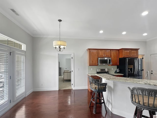 kitchen with light stone countertops, a kitchen bar, appliances with stainless steel finishes, and dark wood finished floors