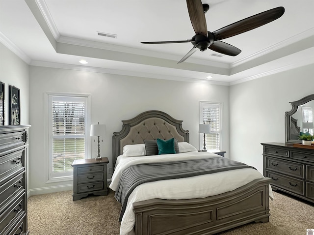 bedroom featuring ceiling fan, light carpet, visible vents, ornamental molding, and a tray ceiling