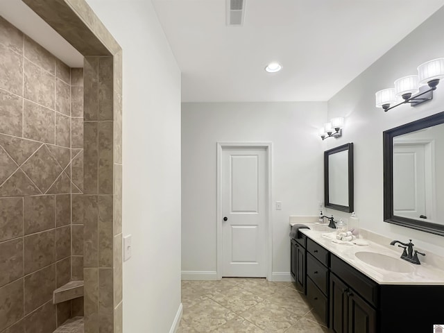 full bathroom with a sink, visible vents, baseboards, tiled shower, and double vanity