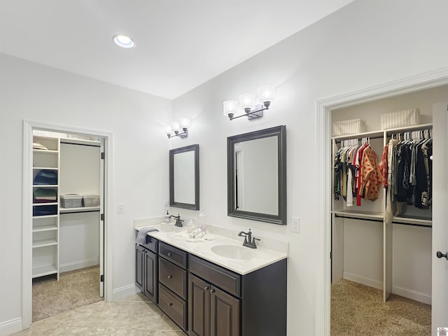 full bath with a walk in closet, a sink, baseboards, and double vanity