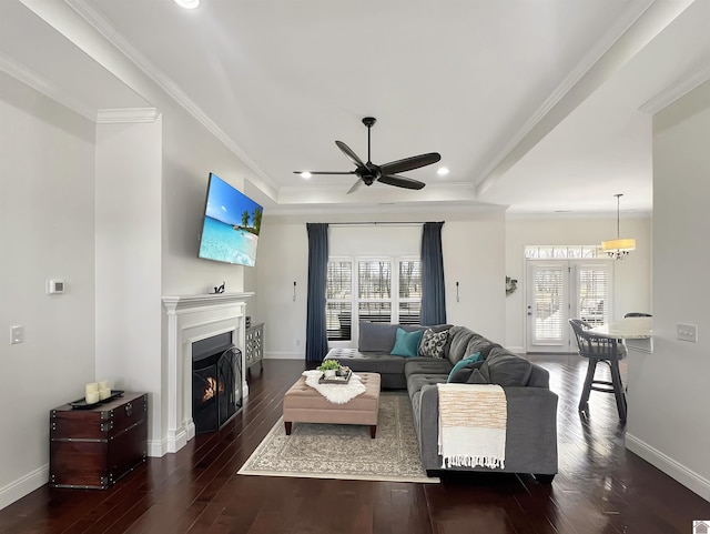 living room with plenty of natural light, a tray ceiling, and wood finished floors