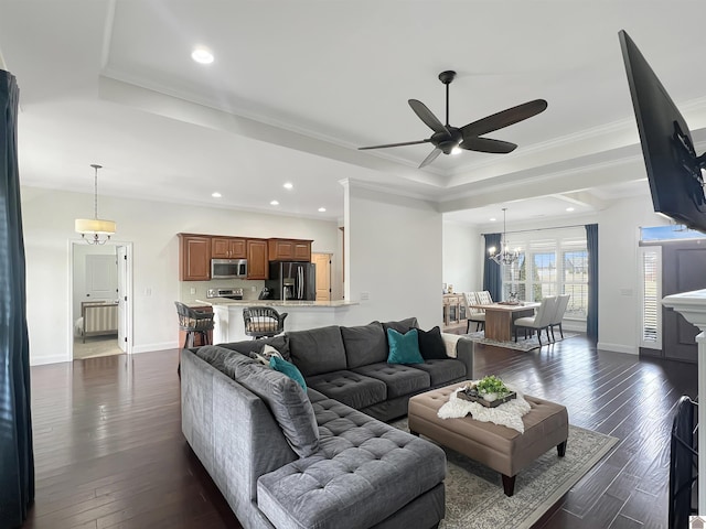 living room with a tray ceiling, radiator heating unit, dark wood-type flooring, ornamental molding, and baseboards