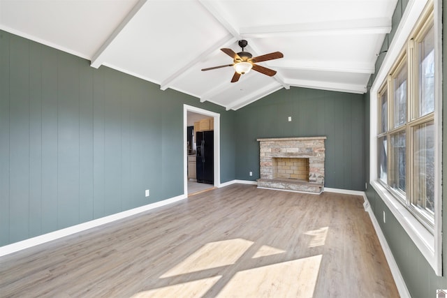 unfurnished living room featuring lofted ceiling with beams, a fireplace, baseboards, and wood finished floors