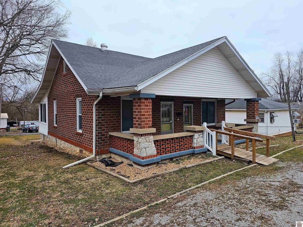 view of front of house with brick siding, a porch, and a shingled roof