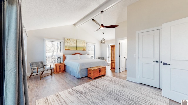 bedroom featuring light wood-style floors, a textured ceiling, baseboards, and beam ceiling