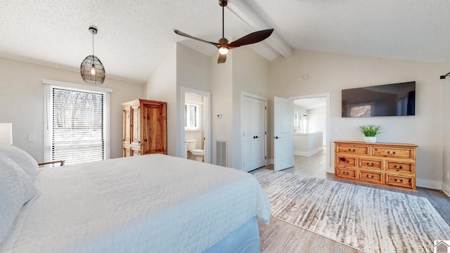 bedroom featuring vaulted ceiling with beams, visible vents, connected bathroom, a textured ceiling, and wood finished floors