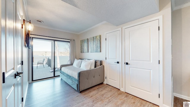 bedroom featuring access to exterior, crown molding, visible vents, light wood-style flooring, and a textured ceiling