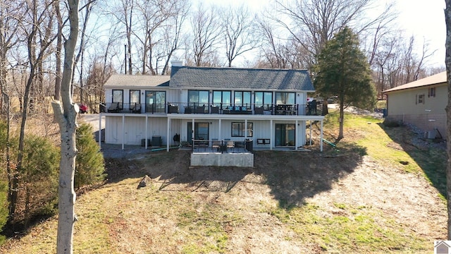 rear view of property featuring a chimney, board and batten siding, a patio area, and a wooden deck