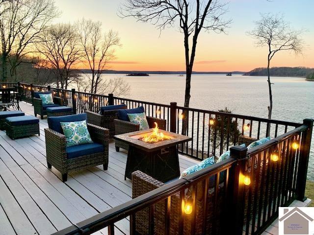 deck at dusk featuring an outdoor living space with a fire pit and a water view