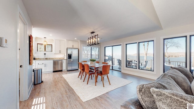 dining area featuring light wood-type flooring, a notable chandelier, and recessed lighting