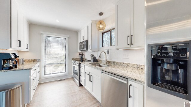 kitchen with visible vents, a sink, light stone countertops, stainless steel appliances, and backsplash