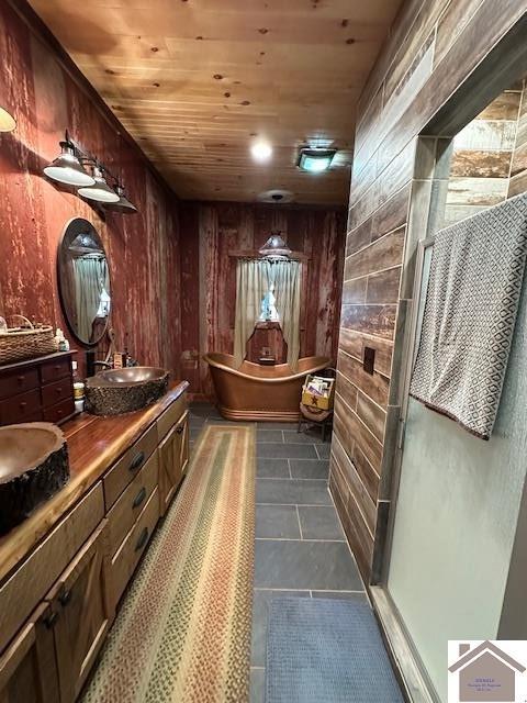 bathroom with a freestanding tub, wooden ceiling, wood walls, and tile patterned floors