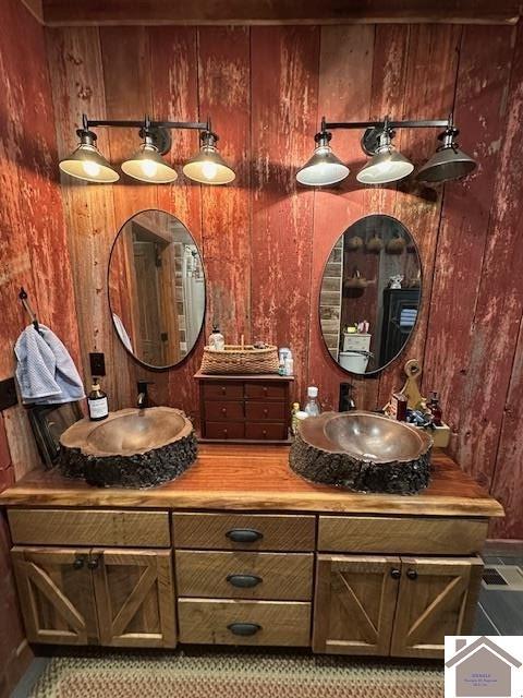 full bathroom featuring double vanity, a sink, and wooden walls