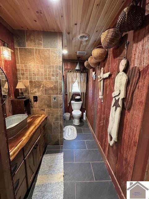 bathroom with tile walls, visible vents, toilet, wood ceiling, and tile patterned floors