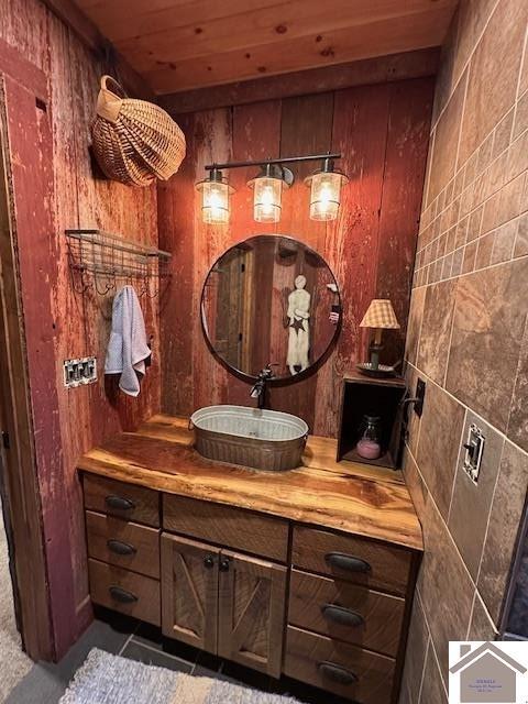 bathroom with wood walls, wood ceiling, and vanity