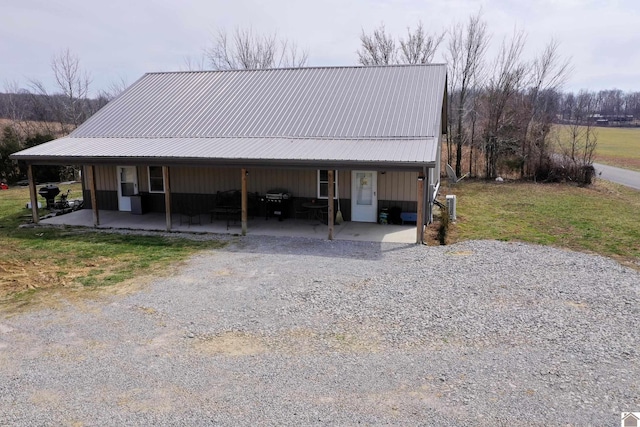 view of front of property featuring metal roof, an attached carport, a front yard, and driveway