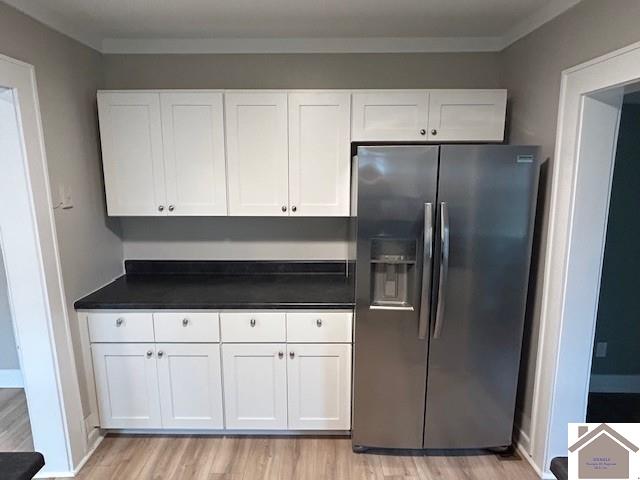 kitchen featuring dark countertops, light wood-type flooring, white cabinets, and stainless steel fridge with ice dispenser