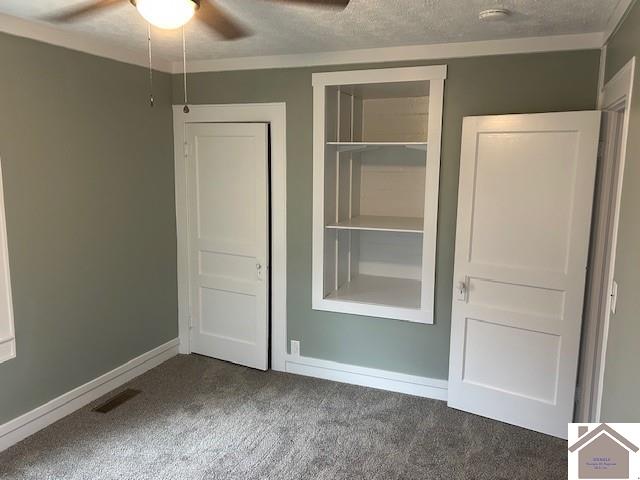 unfurnished bedroom featuring carpet floors, visible vents, a textured ceiling, and baseboards