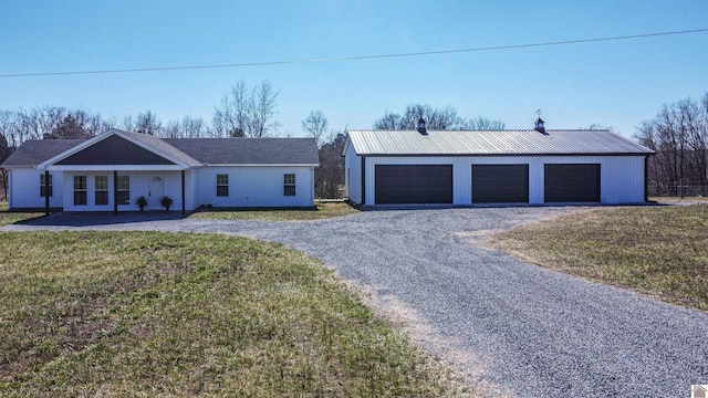 view of front of property with an outbuilding, metal roof, a detached garage, and a front yard