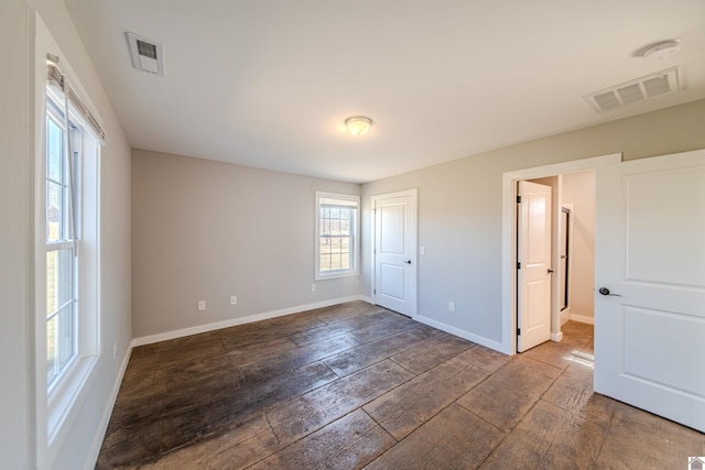 unfurnished bedroom with wood finished floors, visible vents, and baseboards