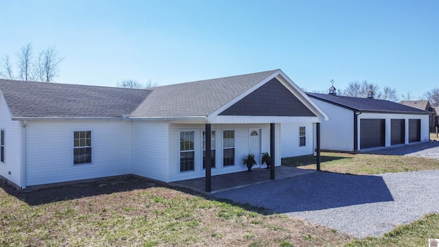 view of front of home featuring a garage, roof with shingles, a front lawn, and an outbuilding