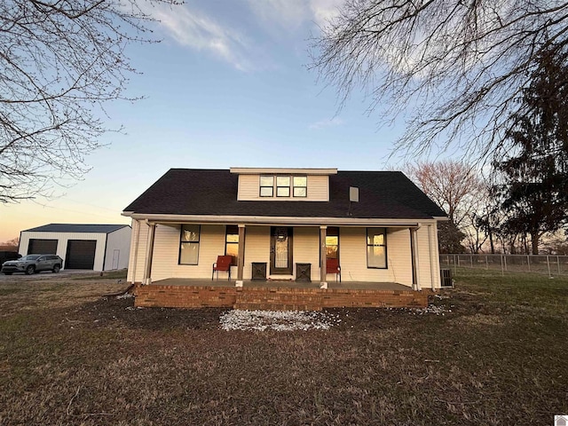 view of front of house with a garage, covered porch, fence, and an outbuilding