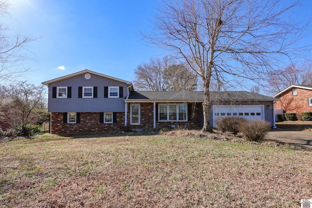 split level home with an attached garage, driveway, a front lawn, and brick siding