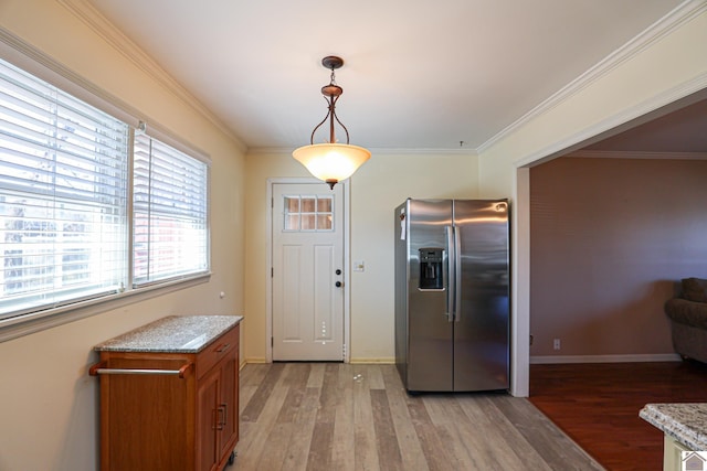 kitchen with brown cabinetry, stainless steel fridge, light wood-style floors, and crown molding