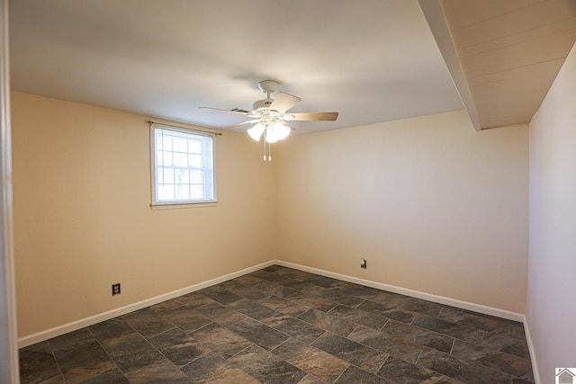 spare room with stone finish flooring, baseboards, and a ceiling fan