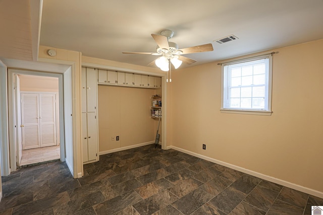 interior space with a ceiling fan, stone finish flooring, visible vents, and baseboards