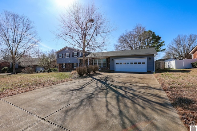 split level home featuring brick siding, driveway, an attached garage, and fence