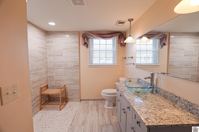 full bathroom featuring visible vents, toilet, vanity, tiled shower, and baseboards