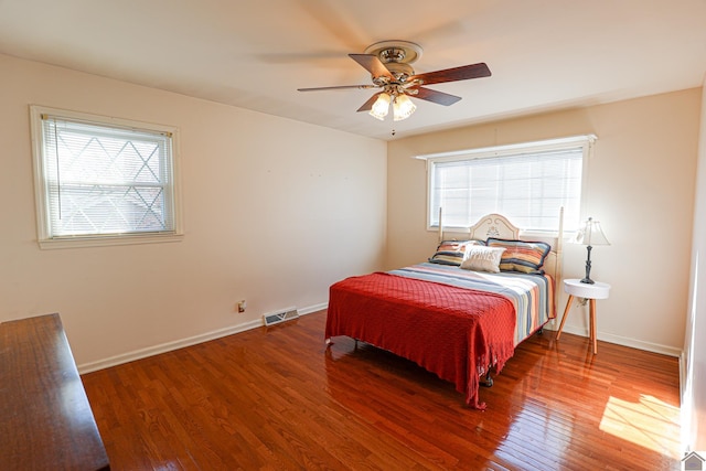 bedroom featuring ceiling fan, wood finished floors, visible vents, and baseboards