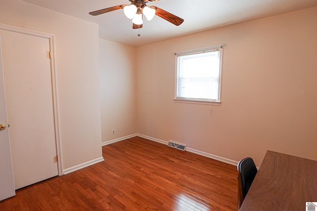 interior space featuring baseboards, visible vents, ceiling fan, and wood finished floors